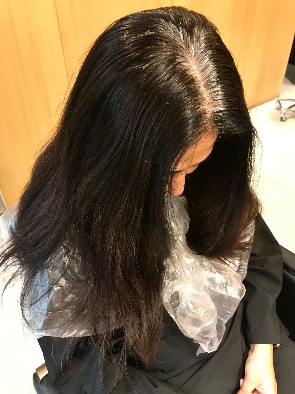 Before colour service showing dense salon-black hair with grey regrowth at the parting
