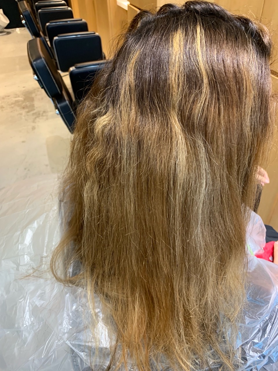 Client B before colour correction, showing dark regrowth and uneven warm blonde lengths